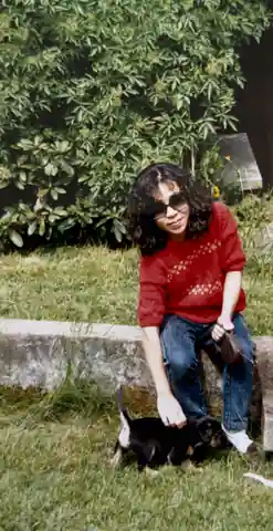 Tomoko seated indoors holding Indy as a small black-and-white puppy.