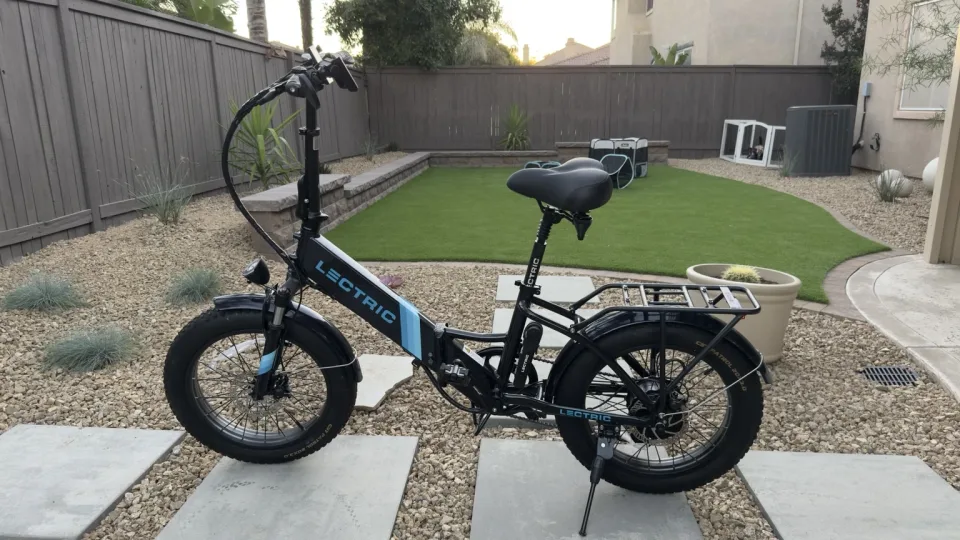 Reverse-side profile showing the Lectric bike frame, folding hinge, rear rack, fenders, and drivetrain
